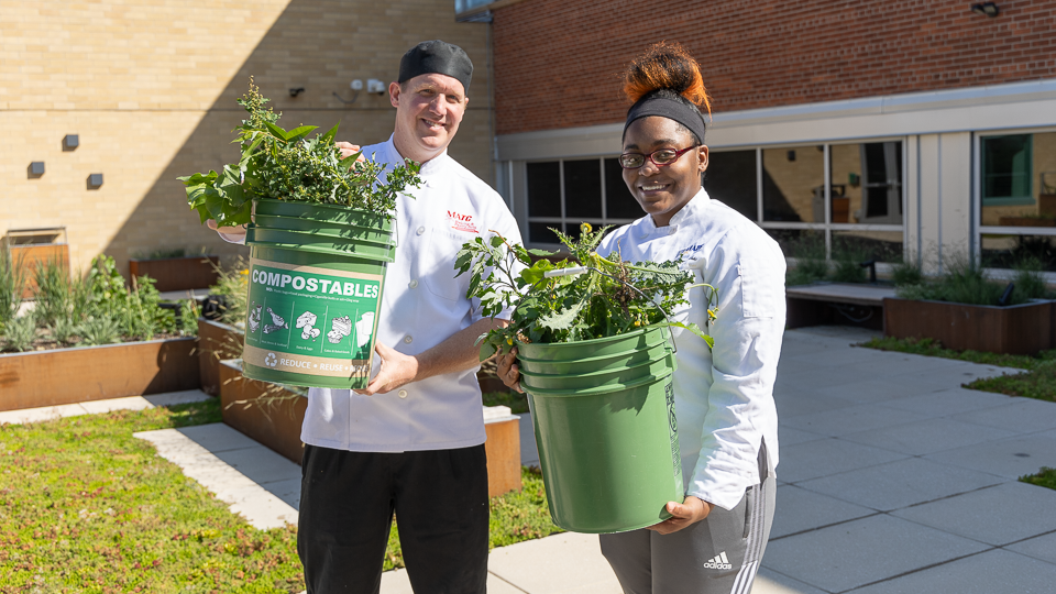 Instructor and Student collecting compostable material in compost buckets