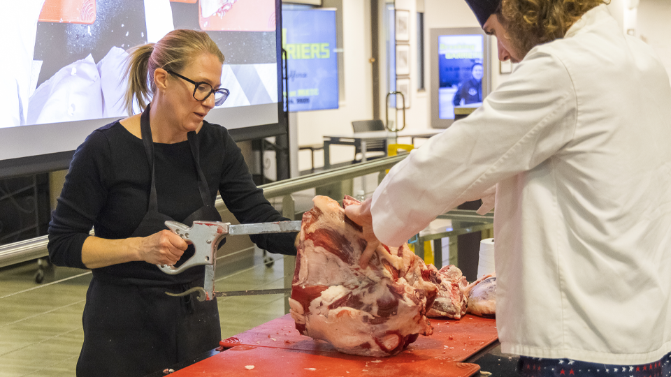 Karen is cutting lamb with a saw